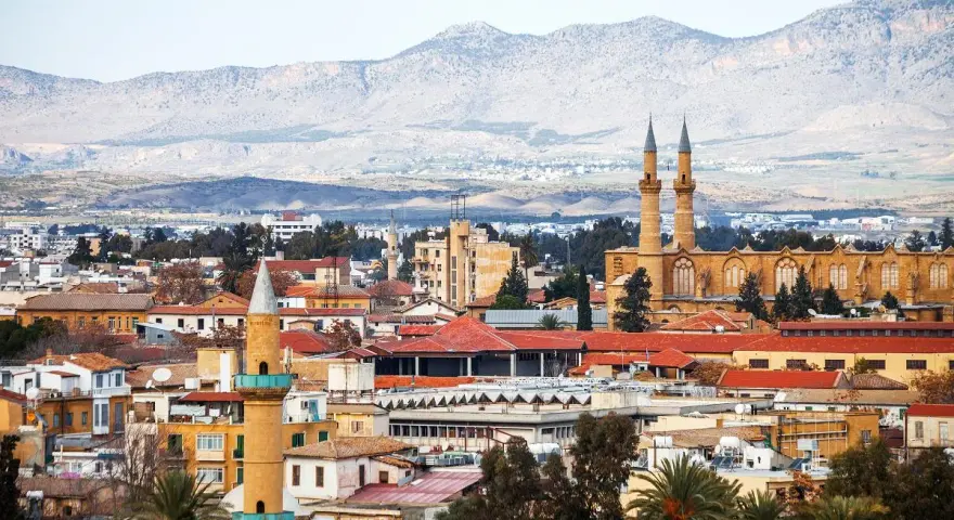 Widok na miasto z minaretami i budynkami o czerwonych dachach, w tle góry. To stolica Cypru, Nikozja.