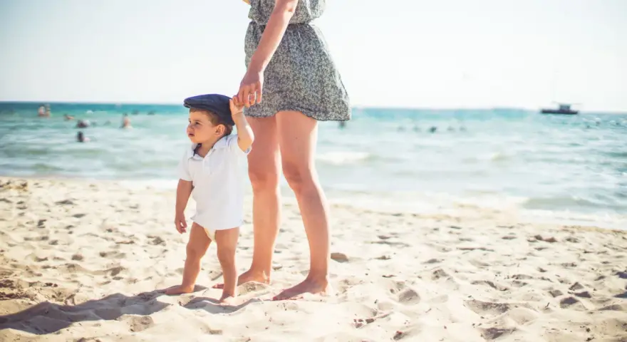 Mama i dziecko na plaży, idealne miejsce, by zapytać, gdzie lecieć w kwietniu. Słońce, piasek i morze.
