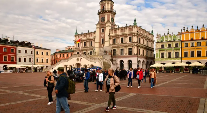 Rynek w Zamościu, idealne miejsce na wycieczki objazdowe z Lublina. Kolorowe kamienice i ratusz tworzą malowniczą scenerię dla spacerujących turystów.