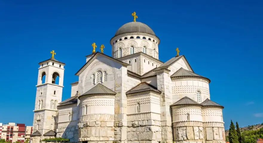 Majestatyczna cerkiew w Podgoricy, jedna z głównych atrakcji miasta, z dominującą kopułą i dzwonnicą na tle błękitnego nieba.