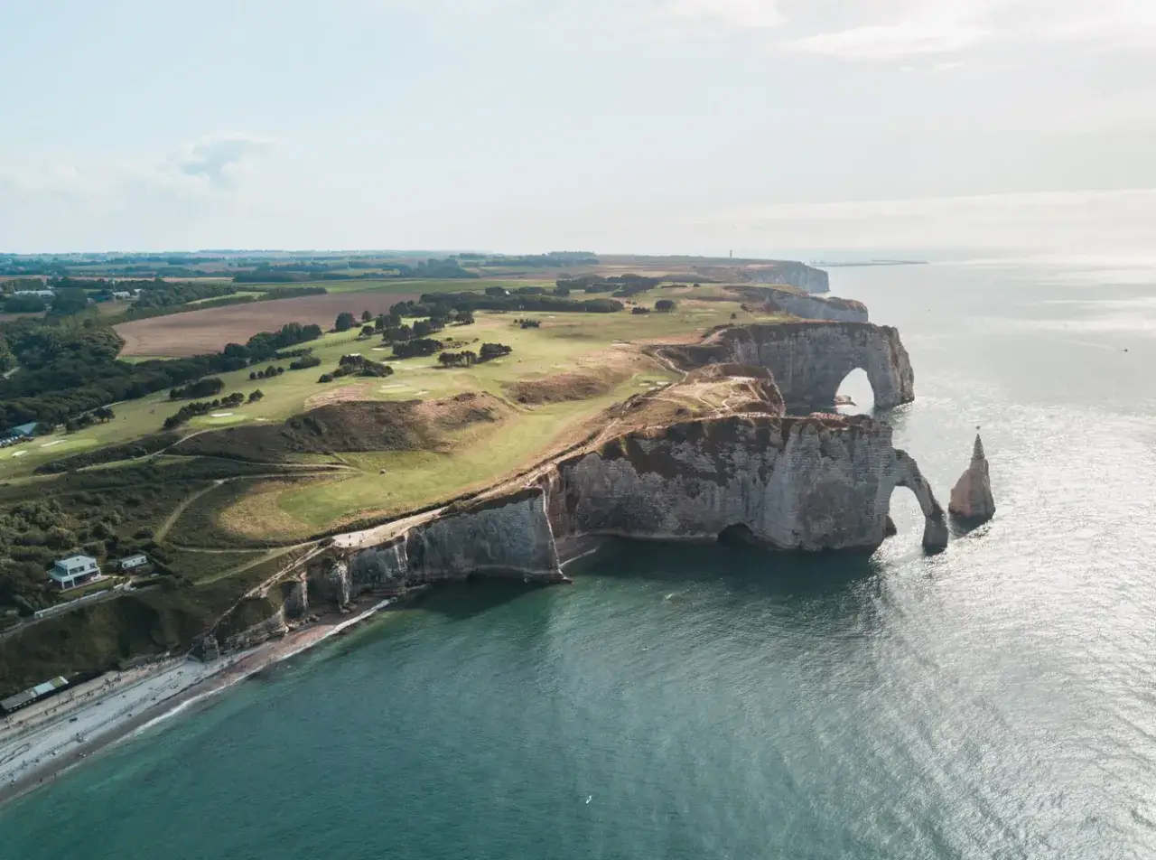 Wspaniałe klify i łuki skalne w Etretat, jedne z najpiękniejszych atrakcji Francji. Widok na pole golfowe i plażę.