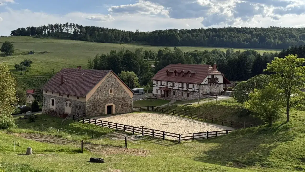 Malownicze gospodarstwo agroturystyczne Dolny Śląsk z ujeżdżalnią, kamiennymi budynkami i otaczającymi lasami.