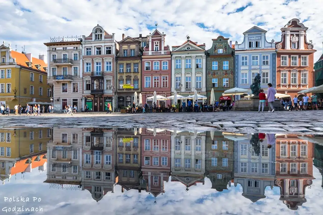 Kolorowe kamienice na Starym Rynku w Poznaniu odbijają się w kałuży. To jedna z gł&oacute;wnych poznan atrakcje.