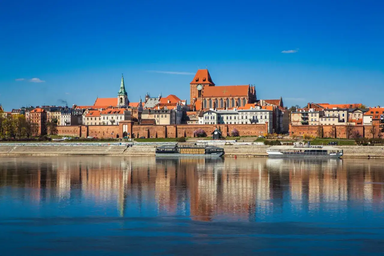 Widok na zabytkowe centrum Torunia z Wisłą w tle. To idealne miejsce, by zobaczyć gotycką architekturę i poczuć ducha historii.